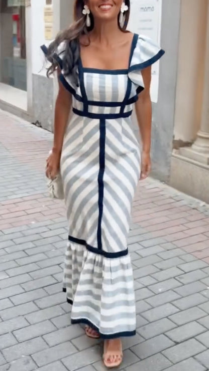 Woman wearing a blue and white striped dress on a city street.
