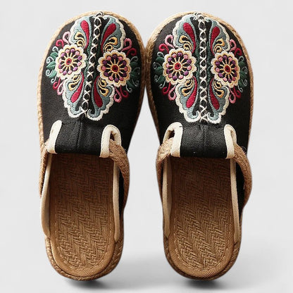 Pair of embroidered sandals with colorful floral patterns on a light gray background