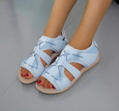 Light blue sandals worn by a person on a gray floor