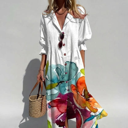 Woman wearing a white shirt with colorful floral pattern holding a straw bag against a plain background