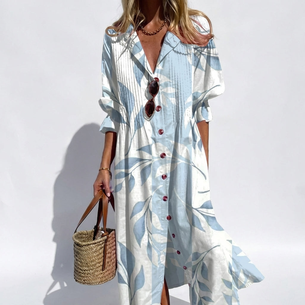 Woman wearing a long, light blue dress with leaf patterns against a white background