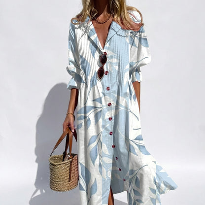 Woman wearing a long, light blue dress with leaf patterns against a white background