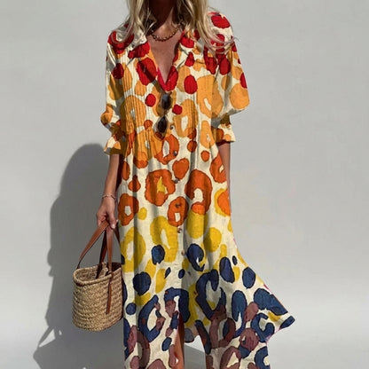 Woman wearing a colorful patterned dress holding a straw bag against a plain background