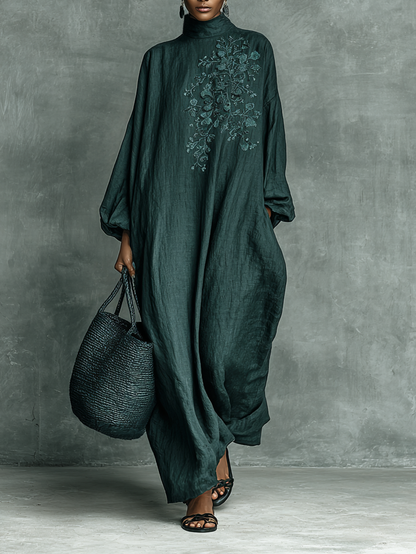 Person wearing a dark green dress with floral embroidery against a gray background