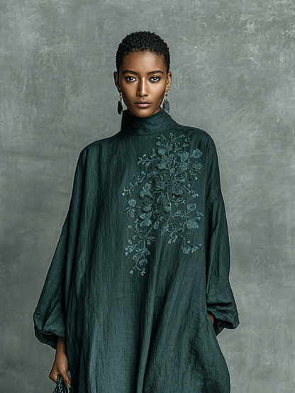 Woman wearing a dark green dress with floral embroidery against a gray background