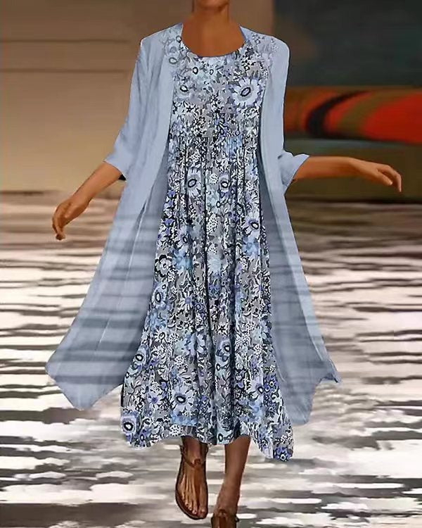 Woman wearing a floral dress with a light blue cardigan on a patterned floor.