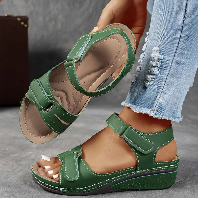 Green sandals worn with light blue jeans on a neutral background