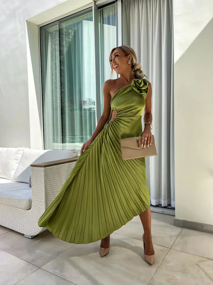 Woman in a green pleated dress standing in a modern indoor setting.
