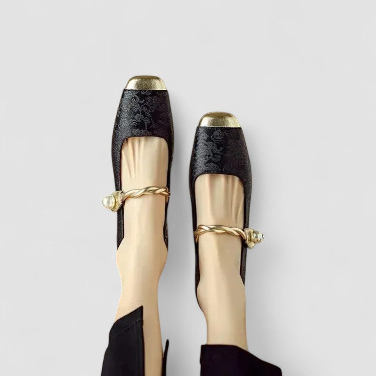 Black and gold shoes with decorative bands on a light gray background