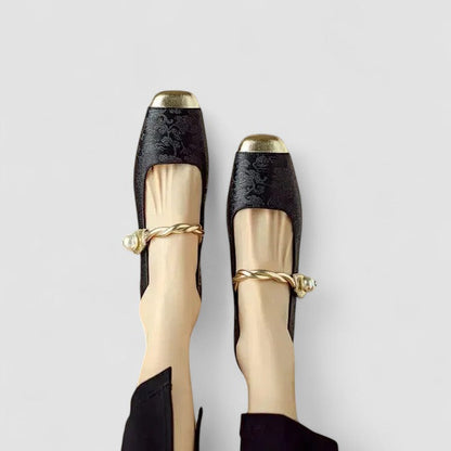 Black and gold shoes with decorative bands on a light gray background