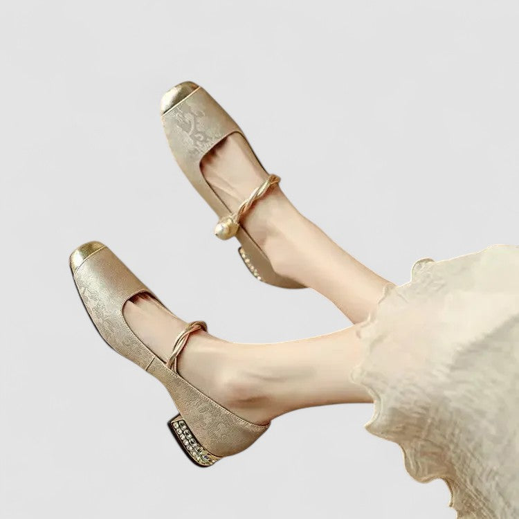 Beige high-heeled shoes with decorative straps on a light gray background