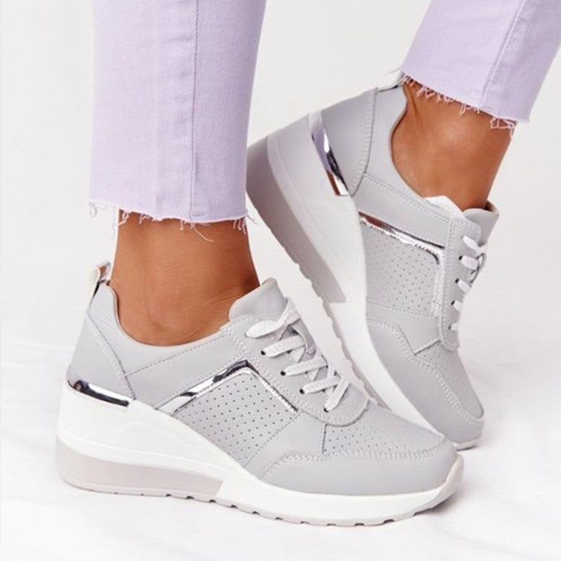Gray sneakers with white soles worn with light purple jeans on a white background