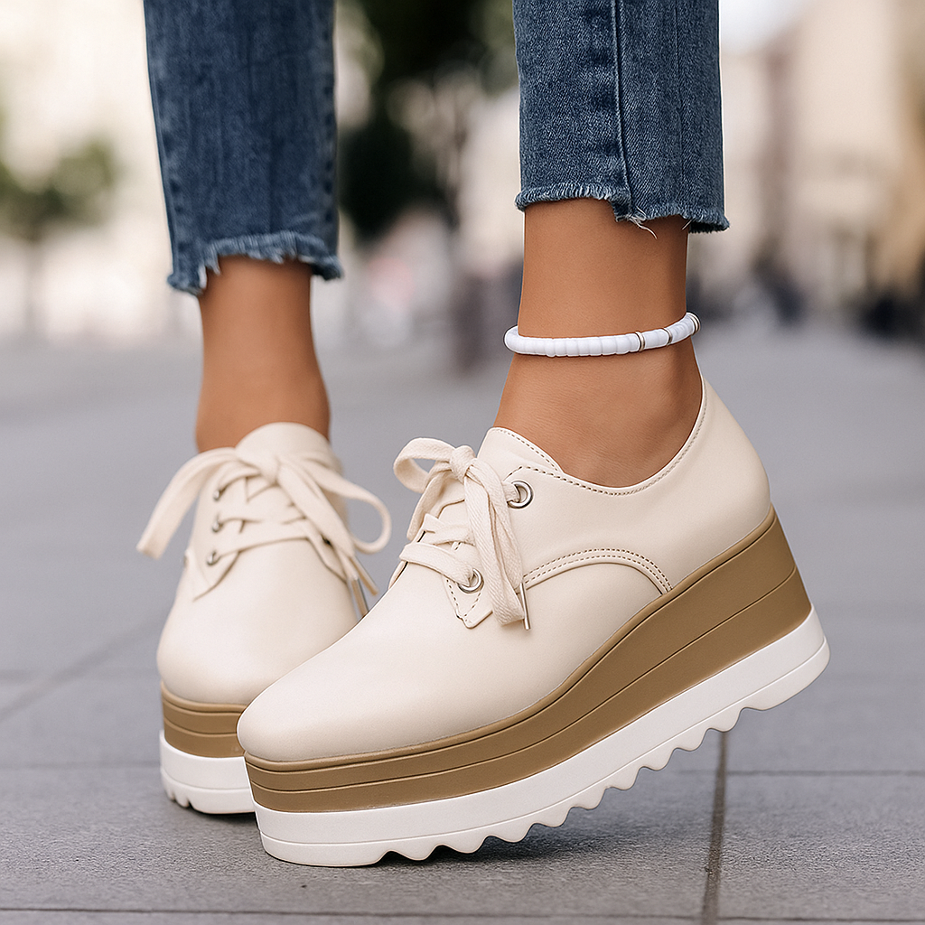 White sneakers with brown soles worn on a blurred street background