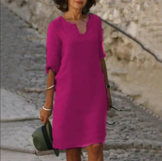 Woman in a pink dress standing on a stone path with a stone wall in the background
