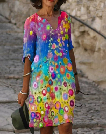 Woman wearing a colorful floral dress standing on a stone path.