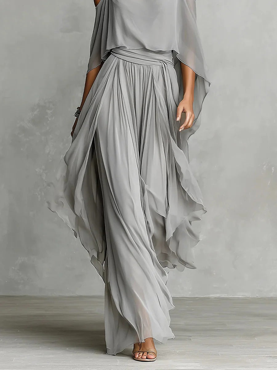 Person wearing a flowing gray dress against a plain background