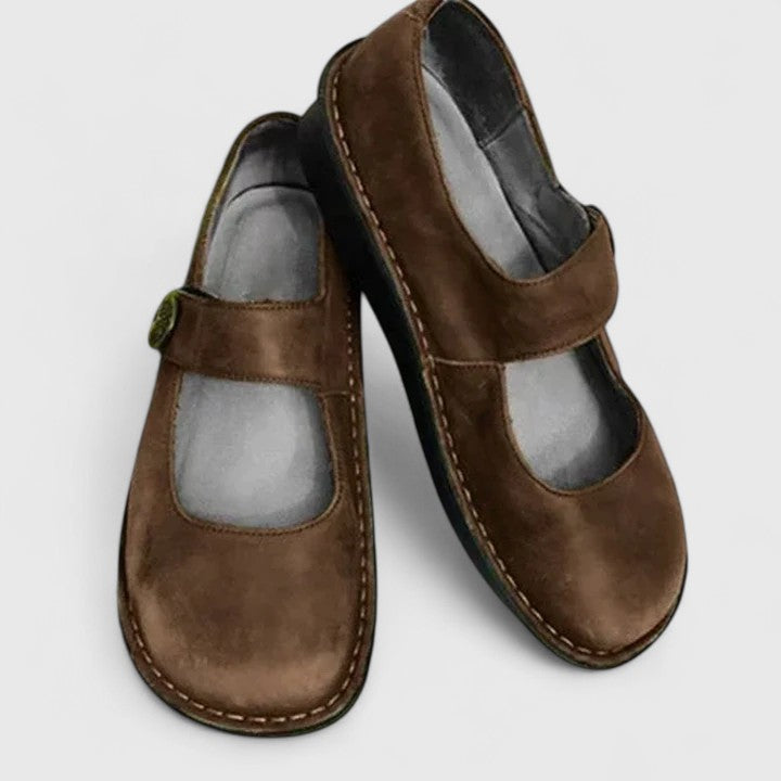 Pair of brown children's shoes with velcro straps on a light gray background