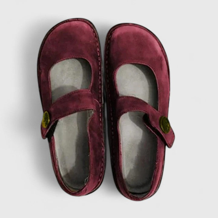 Pair of maroon children's shoes with a strap on a light gray background