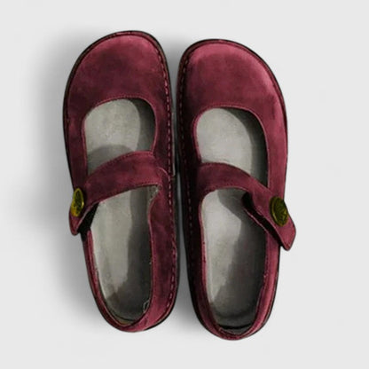 Pair of maroon children's shoes with a strap on a light gray background