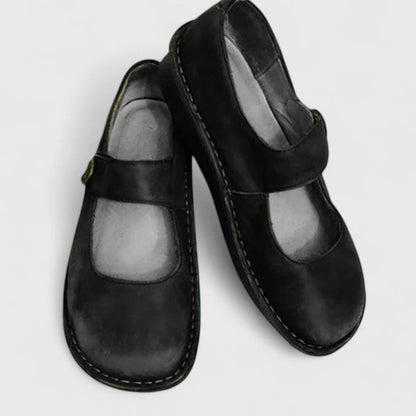Pair of black leather shoes with a strap on a light gray background