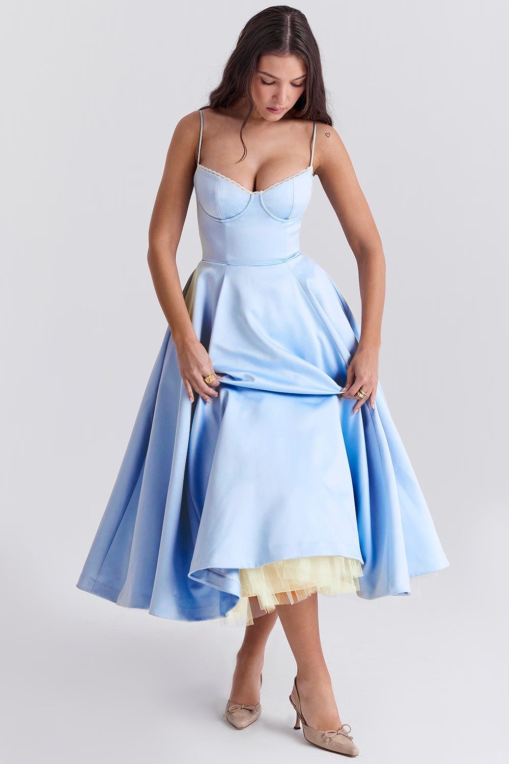 Woman wearing a light blue dress with a yellow hem on a white background