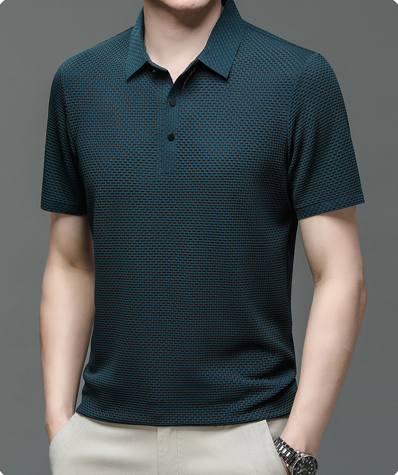 Man wearing a dark green patterned polo shirt on a gray background
