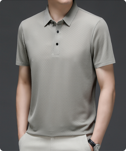 Man wearing a patterned gray polo shirt on a dark background