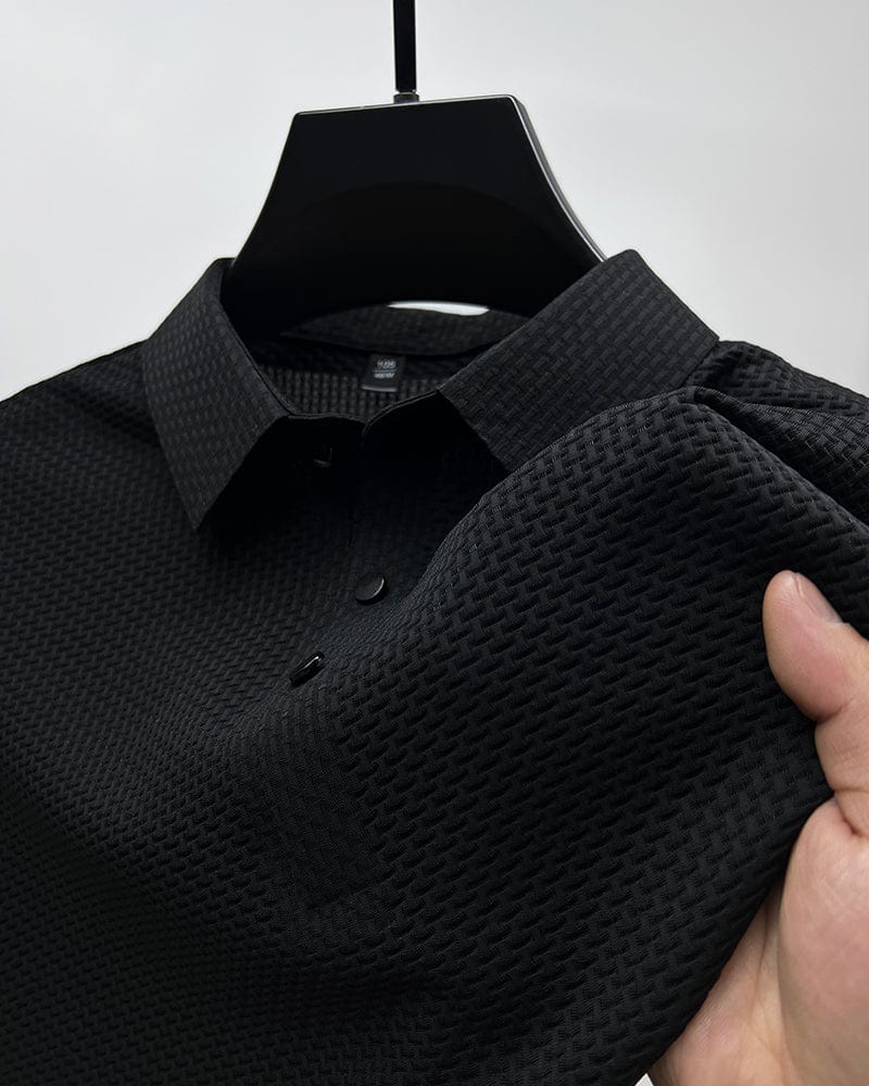Black textured polo shirt on a hanger with a hand holding it