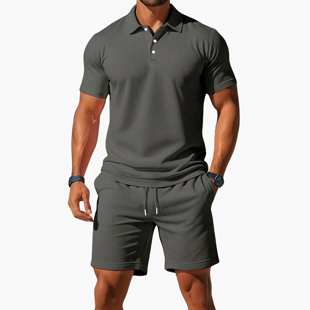 Man wearing a gray polo shirt and shorts set on a white background