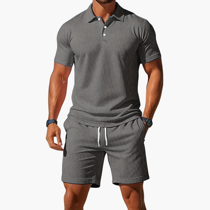 Man wearing a gray polo shirt and shorts set on a white background