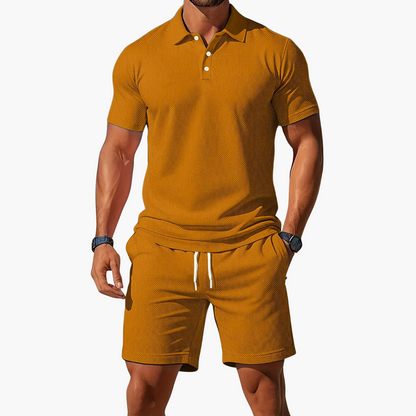 Man wearing a mustard yellow polo shirt and shorts set on a white background
