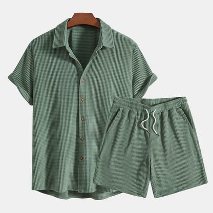 Green checkered shirt and shorts set on a hanger against a white background