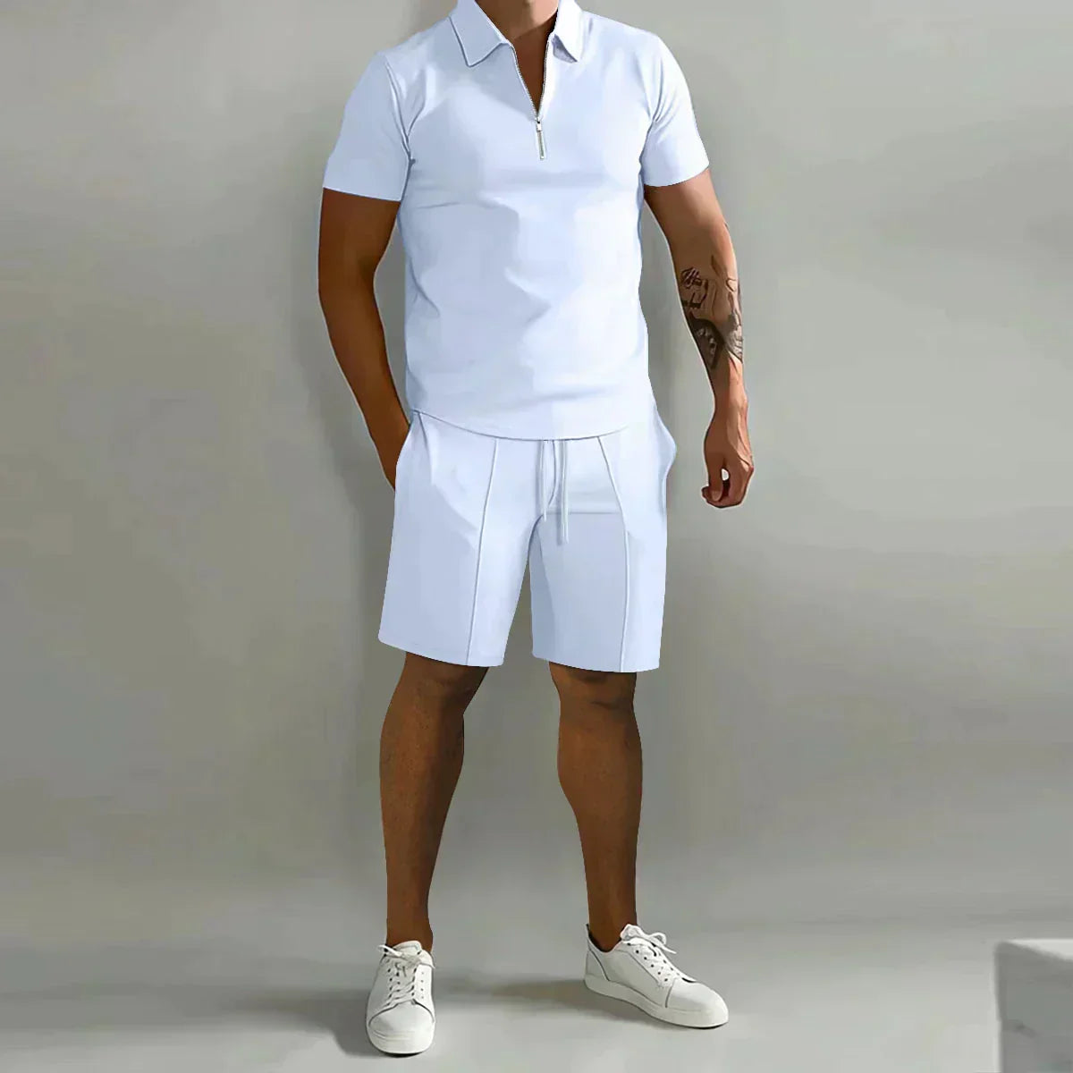 Person wearing a white polo shirt and shorts set with white sneakers on a plain background