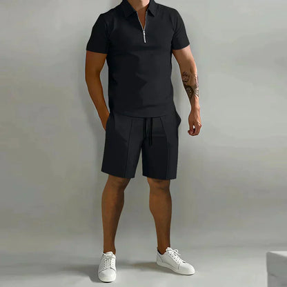 Person wearing a black polo shirt and shorts with white sneakers on a gray background