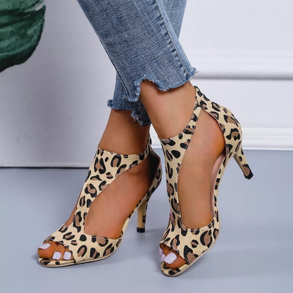 Leopard print high-heeled shoes worn with denim jeans on a neutral background