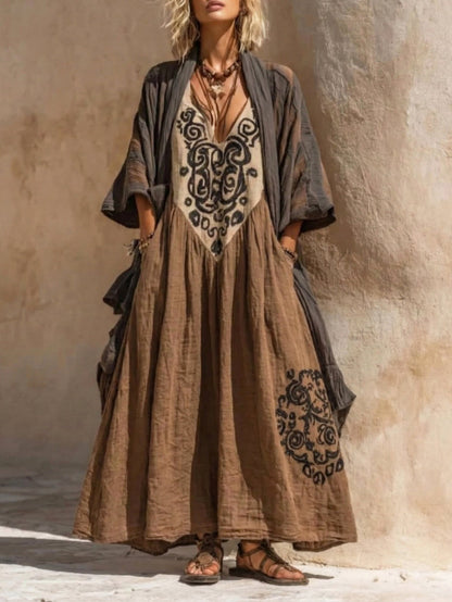 Woman wearing a long, patterned dress with a cardigan against a textured wall.