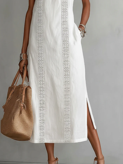 Woman wearing a white dress with intricate patterns, holding a beige bag against a gray background