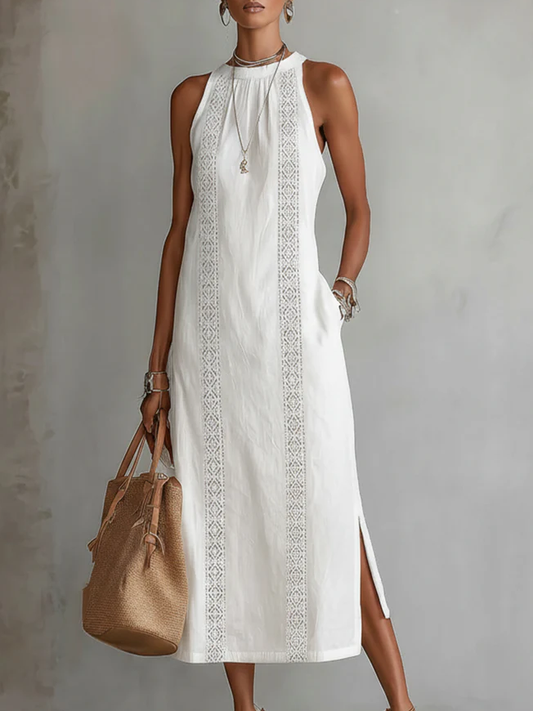 Woman wearing a white dress with lace details and holding a brown handbag against a gray background