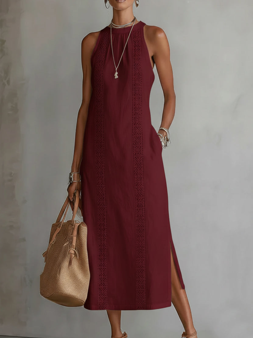 Woman wearing a burgundy dress with a beige handbag against a plain background