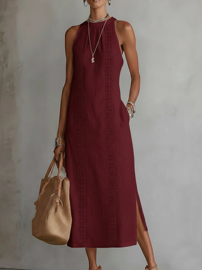 Woman wearing a burgundy dress with a beige handbag against a plain background