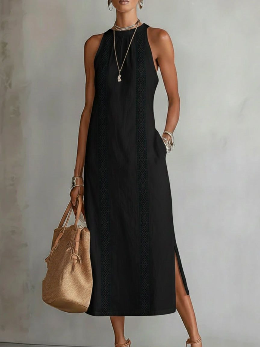 Woman wearing a black sleeveless dress holding a beige bag against a plain background
