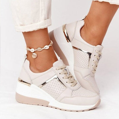 White sneakers with gold accents worn by a person on a white background