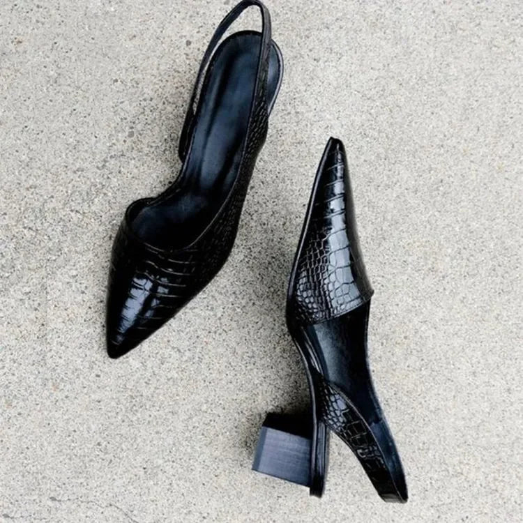 Black crocodile-patterned high-heeled shoes on a light gray surface