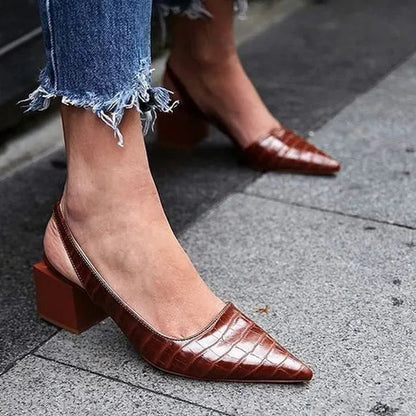 Brown crocodile-patterned shoes worn on a sidewalk