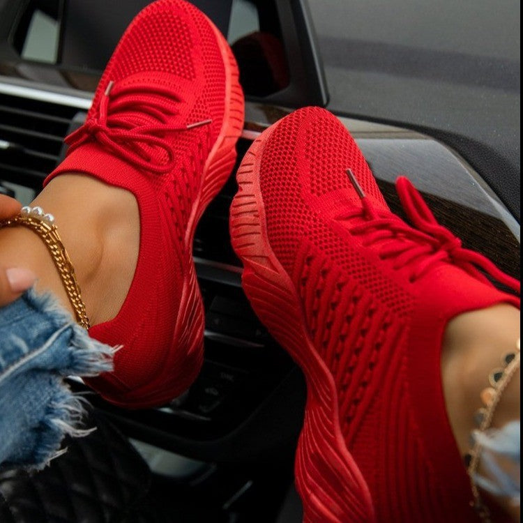 Red sneakers worn with denim shorts, sitting on a car seat.