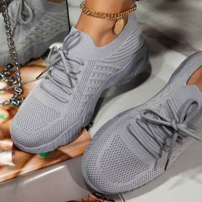 Gray sneakers worn with a gold chain and colorful background