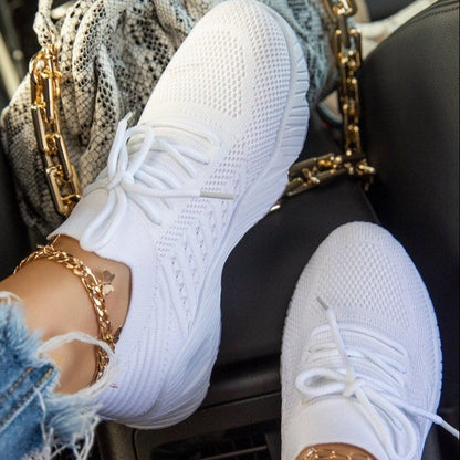 White sneakers worn with gold chains and denim jacket on a car seat.