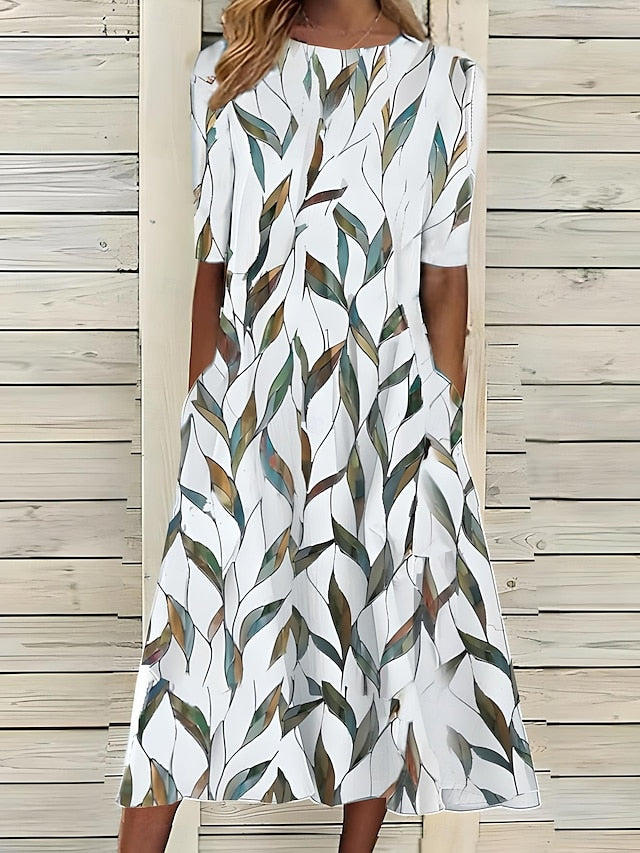 Woman wearing a white dress with green leaf pattern against a wooden background