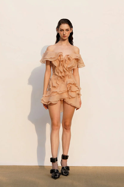 Woman wearing a beige ruffled dress against a plain background