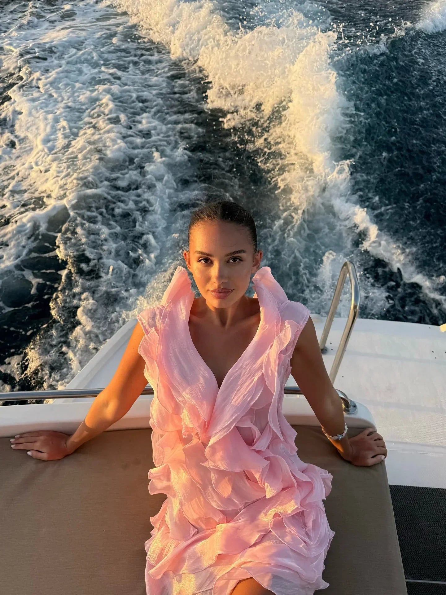 Woman in a pink dress on a boat with water splashing around